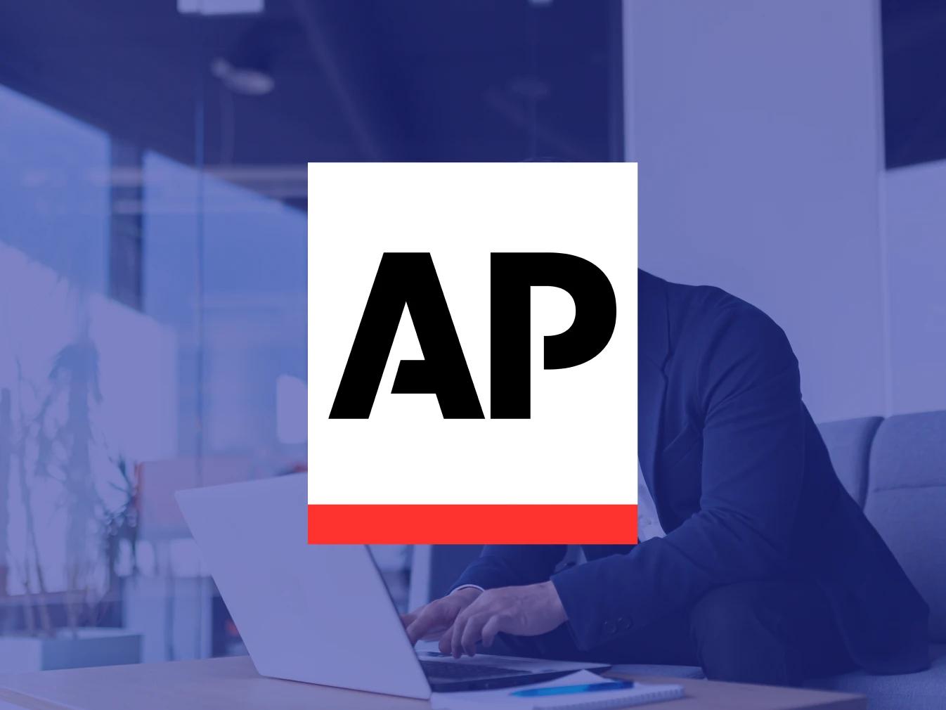 Logo for the Associated Press, a Business Wire partner, overlayed on an image of a man working on a laptop