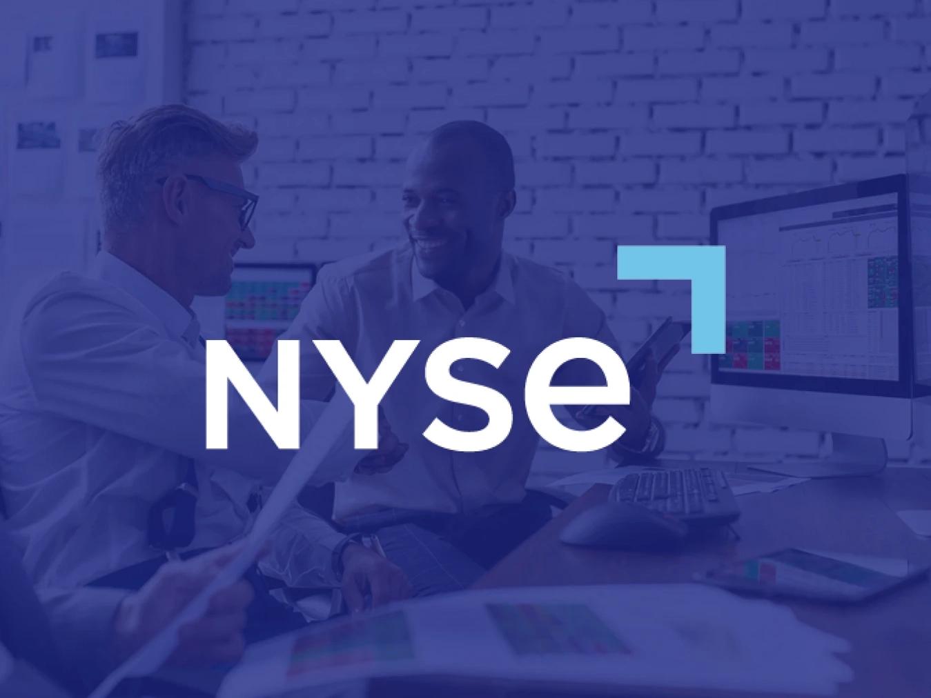 Logo for the New York Stock Exchange, a Business Wire partner, overlayed on an image of two men collaborating on a spreadsheet on a desktop computer