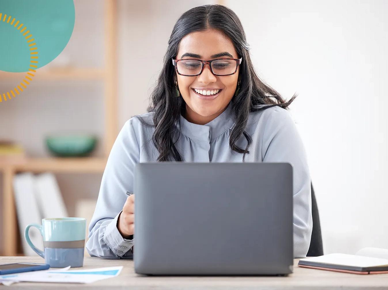 woman smiling while working on a laptop