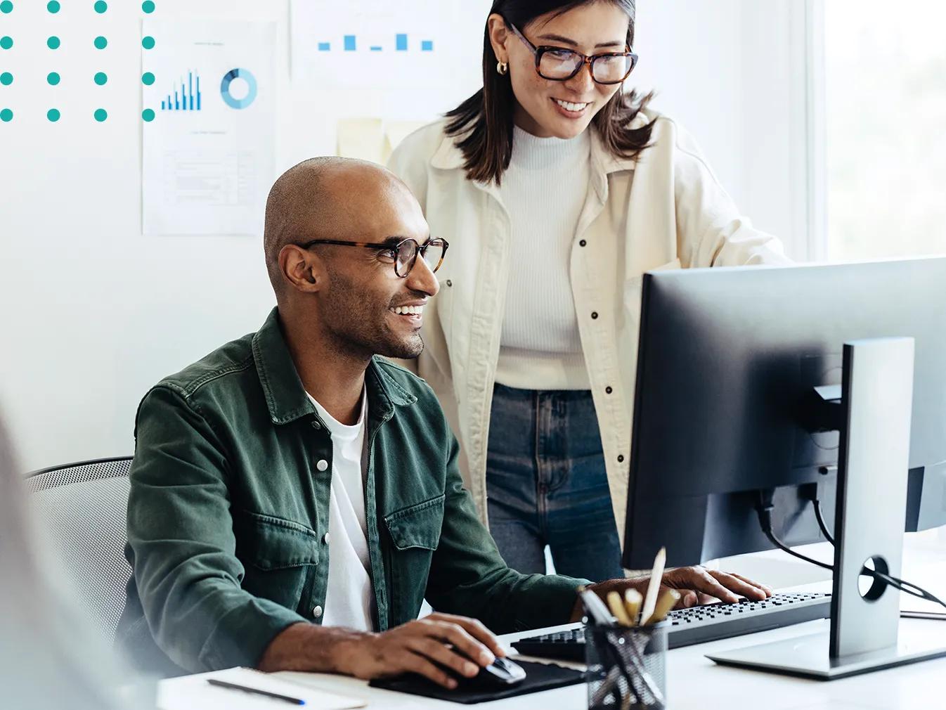 two people collaborating over a desktop computer