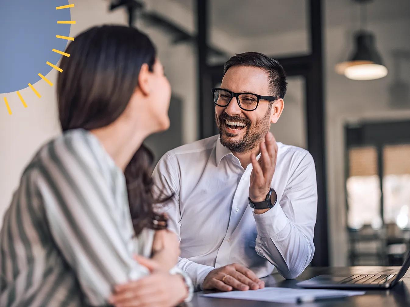 man and woman talking and laughing at a desk